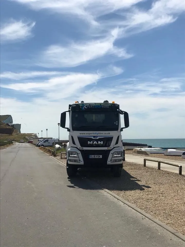 a white skip lorry parked on a sunny day
